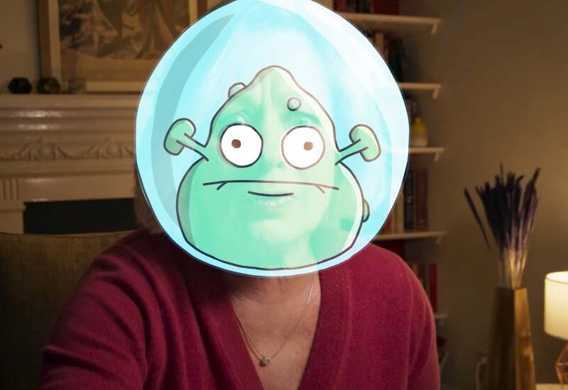A person wearing a digital cartoon alien face filter.